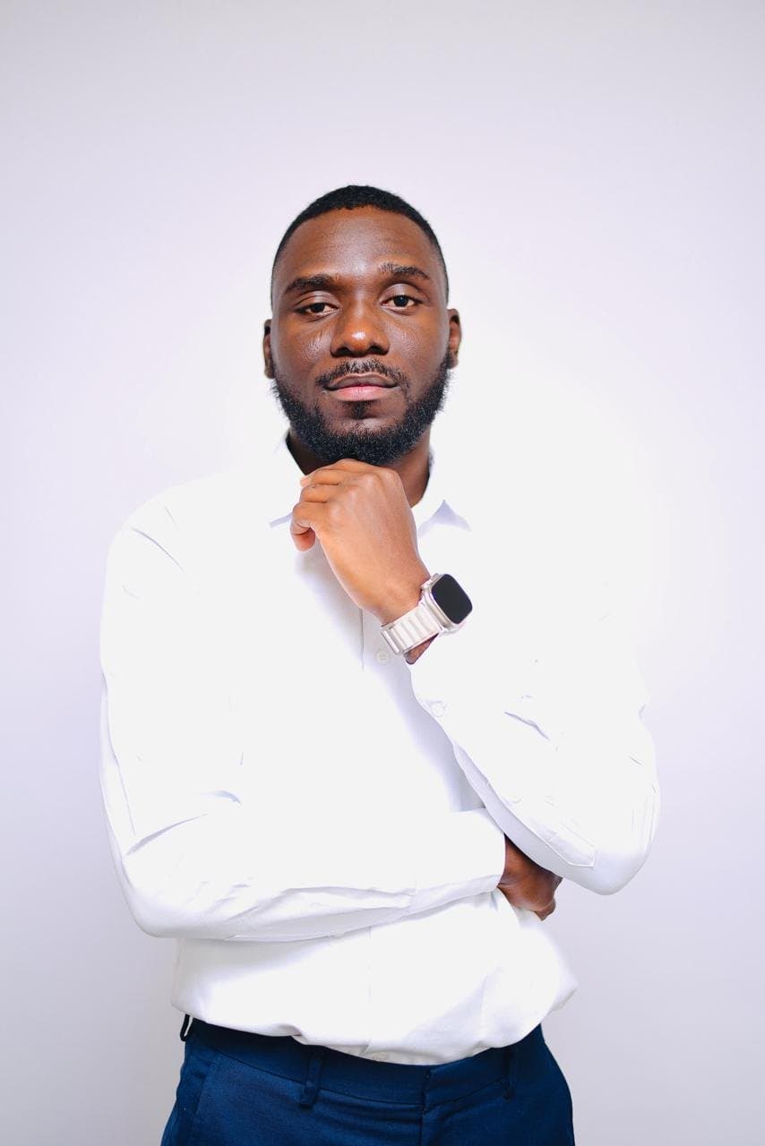 Oyewale in a white shirt, hand under his chin